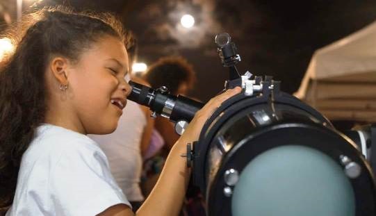menina observando a lua em telescópio